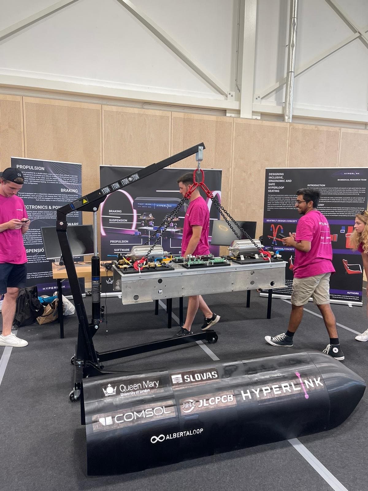 Hyperlink team at workshop with pod shell, gantry crane, and biomedical research posters